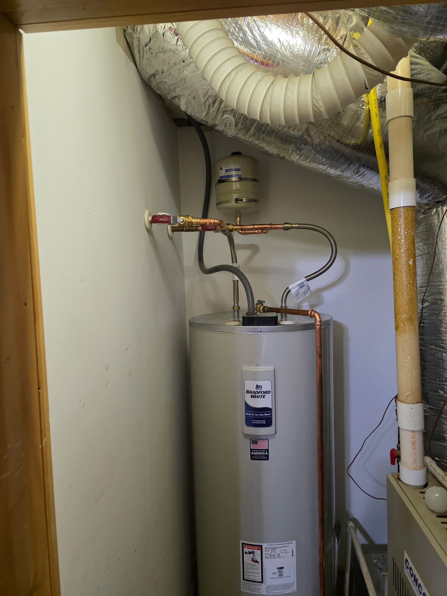Water heater in a white room. Copper pipes, ductwork, and vent pipe visible.