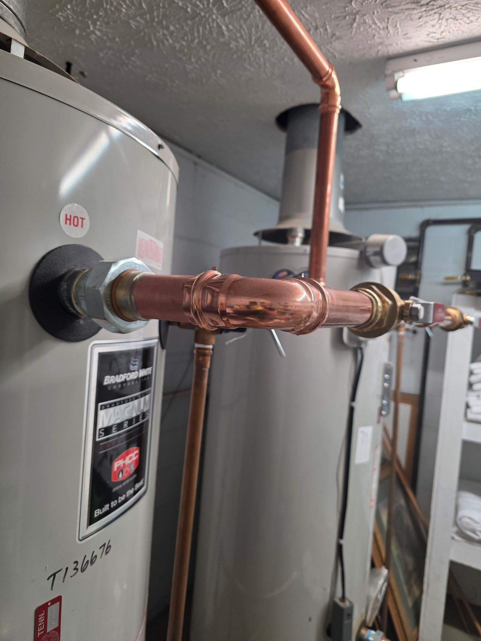 Copper plumbing connected to a water heater and chimney in a utility room.