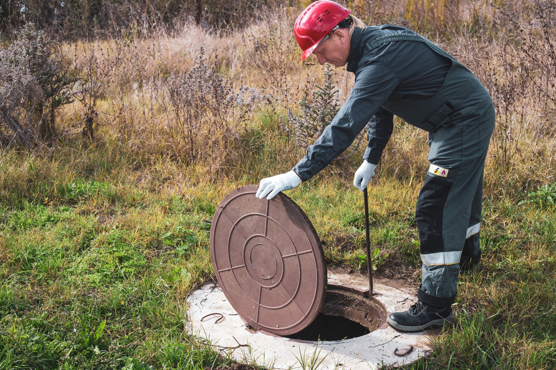A man is opening a septic tank. A man is opening a septic tank.