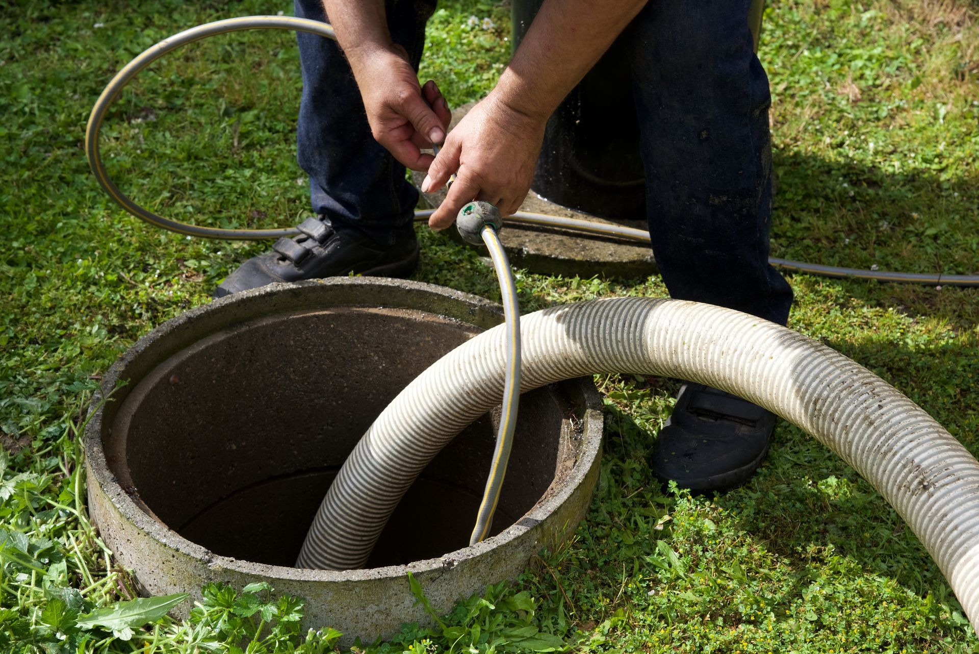 A technician using a hose to flush out a drain line during a septic system repair process. A technician using a hose to flush out a drain line during a septic system repair process.