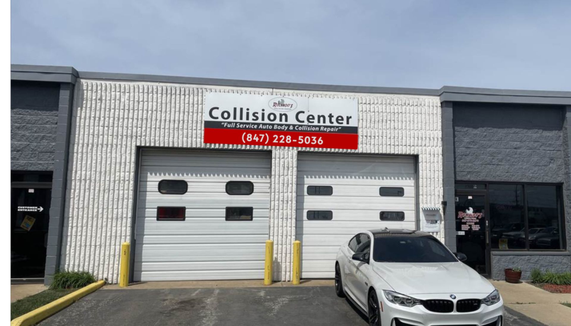 A white car is parked in front of Rolando's Collision Center