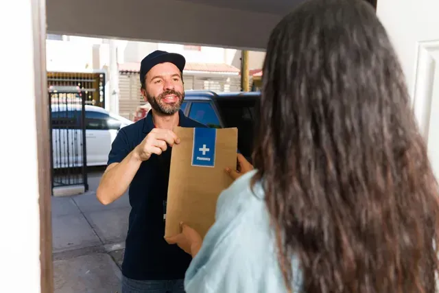 Delivery worker handing a cardboard box to a person at a doorway
