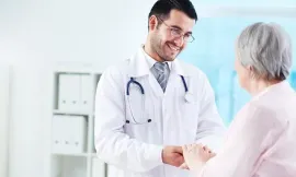 Doctor in white coat shaking hands with an elderly patient in a bright clinic office