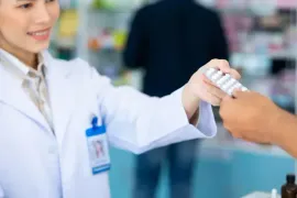 Pharmacist in white coat handing medicine to a customer at a pharmacy counter