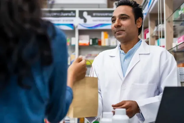 Pharmacist in white coat helping a customer at a pharmacy counter