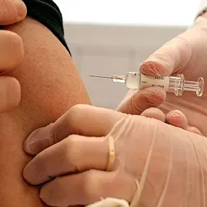 Doctor administering an injection in a patient's arm with gloved hands
