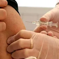 Doctor administering an injection in a patient's arm with gloved hands