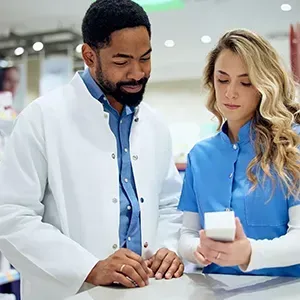 Two pharmacists reviewing a prescription bottle at a pharmacy counter