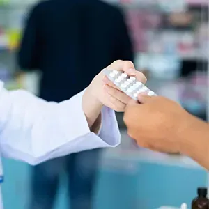 Pharmacist handing medication to a customer at a pharmacy counter