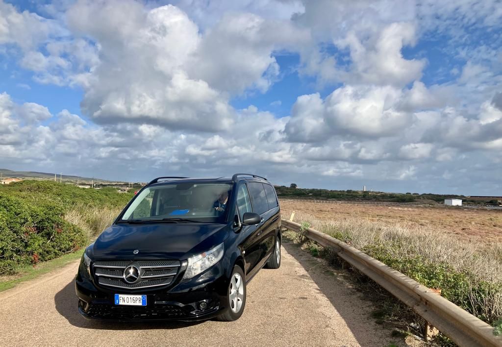 una mercedes benz nera parcheggiata su una strada sterrata