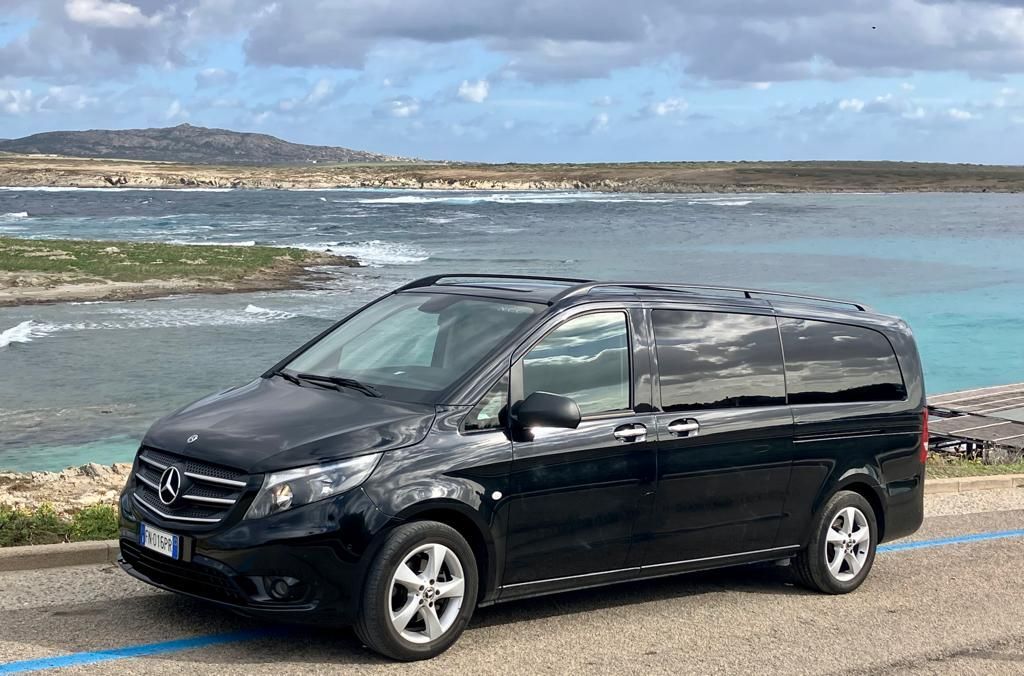 una mercedes nera parcheggiata accanto a una spiaggia
