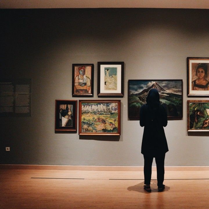 A woman is looking at paintings in a museum