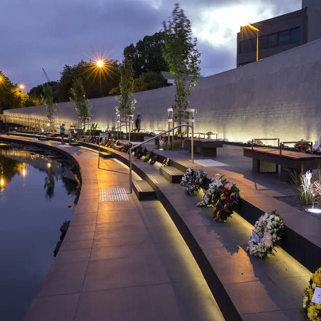 A row of flowers on a sidewalk next to a body of water