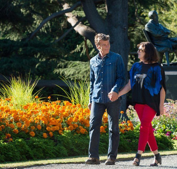 A man and a woman are walking down a path holding hands