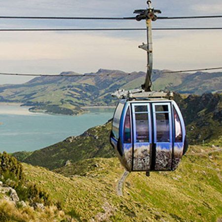 A cable car is going up a hill overlooking a body of water.