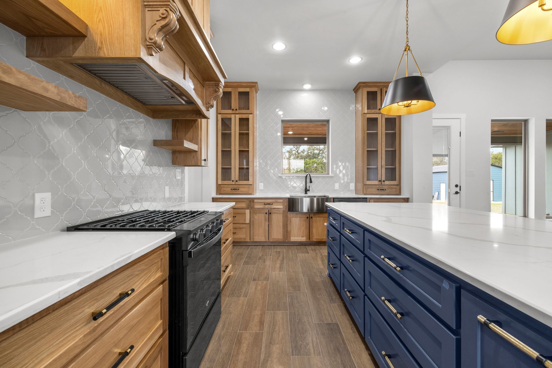 Modern kitchen with wood cabinets, blue island, white countertops, and black stove.