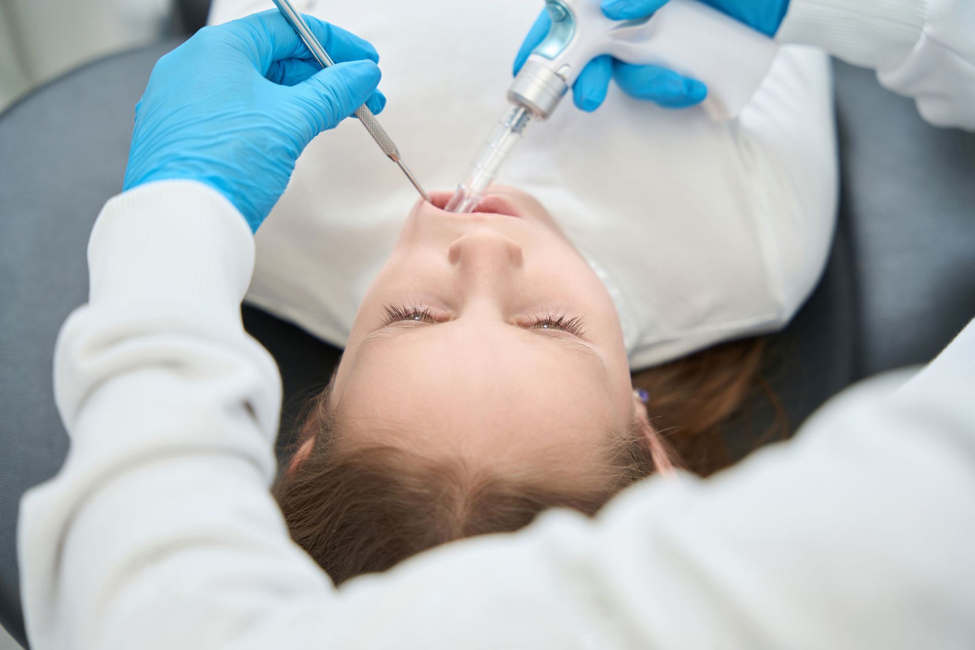 A little girl is getting her teeth examined by a dentist.