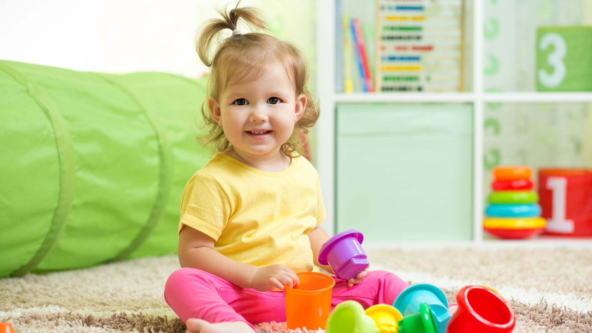 A little girl is sitting on the floor playing with toys.