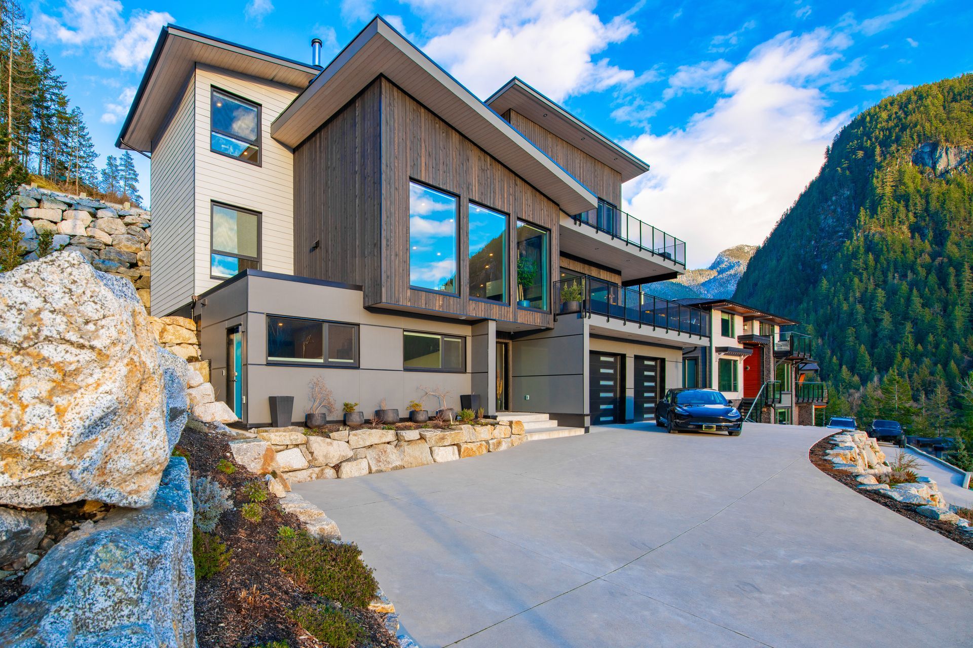 Modern multi-story house with gray and brown siding, a driveway