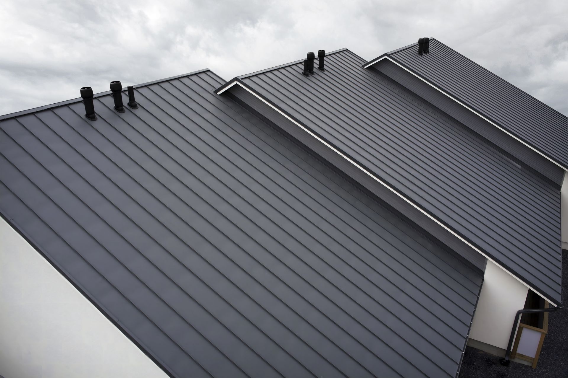 Dark gray metal roof on a building with three sections