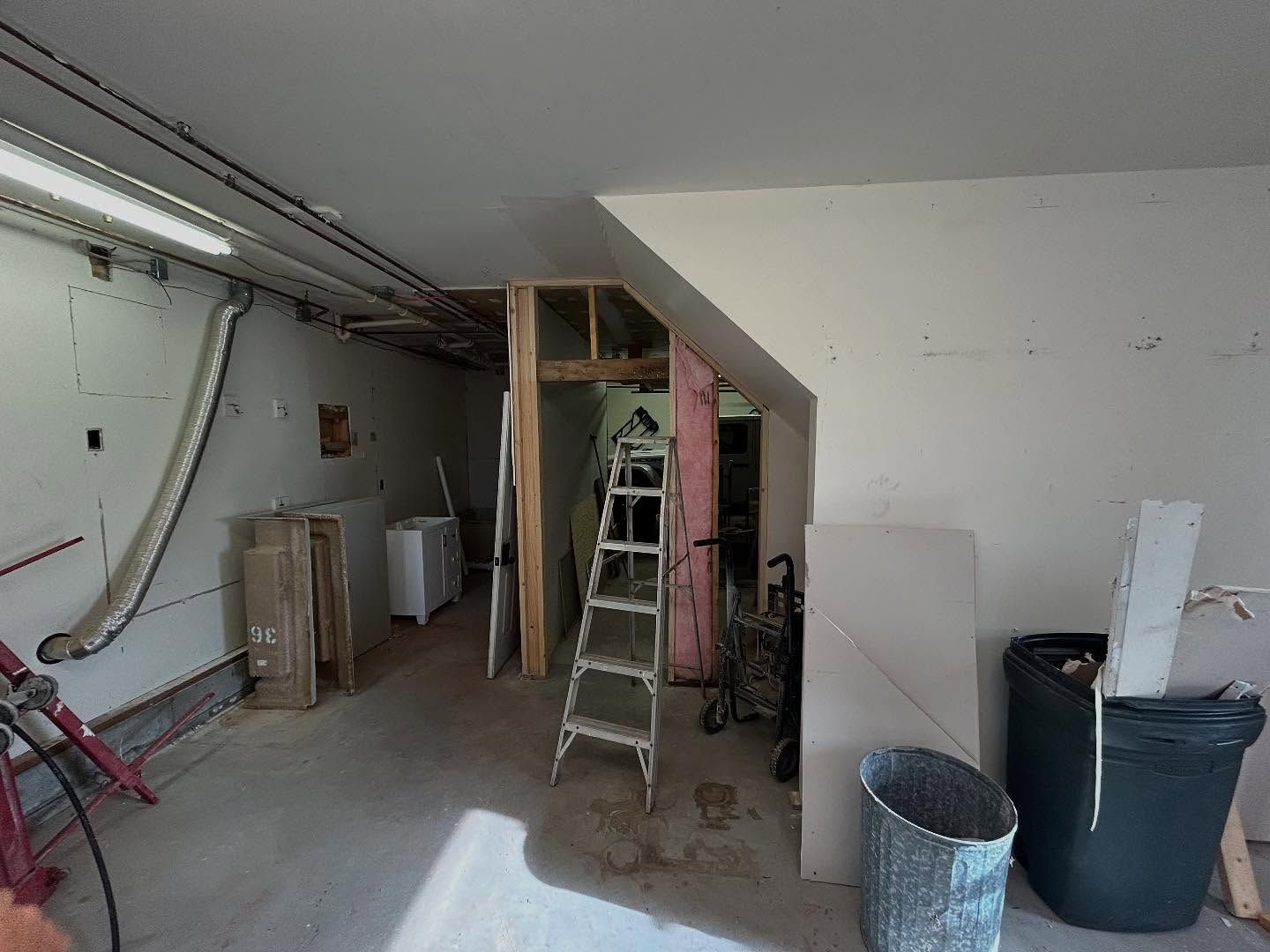 Basement under construction, with exposed framing, ladder, and materials.
