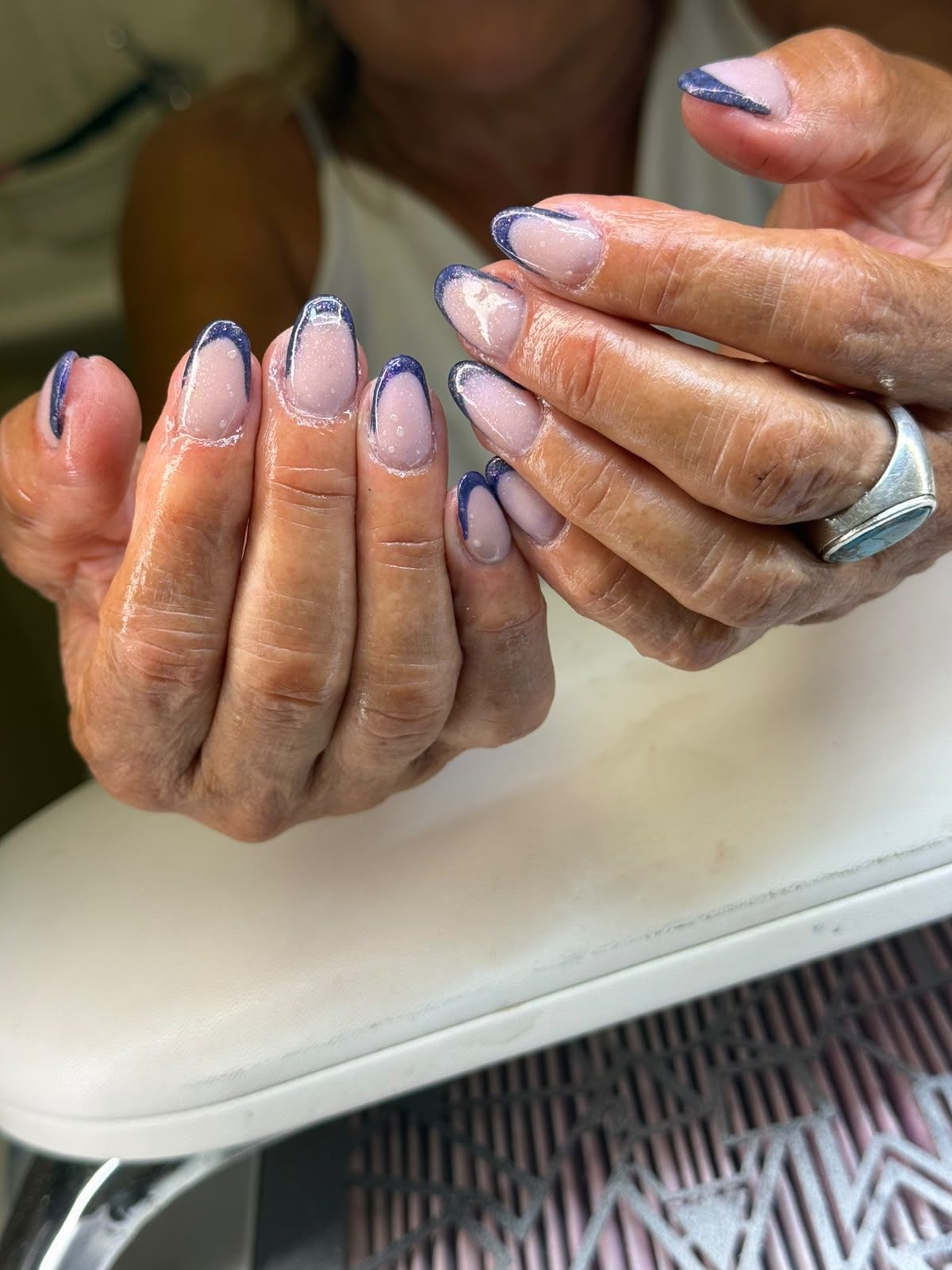 Mani con unghie laccate color lavanda appoggiate su un tavolo.