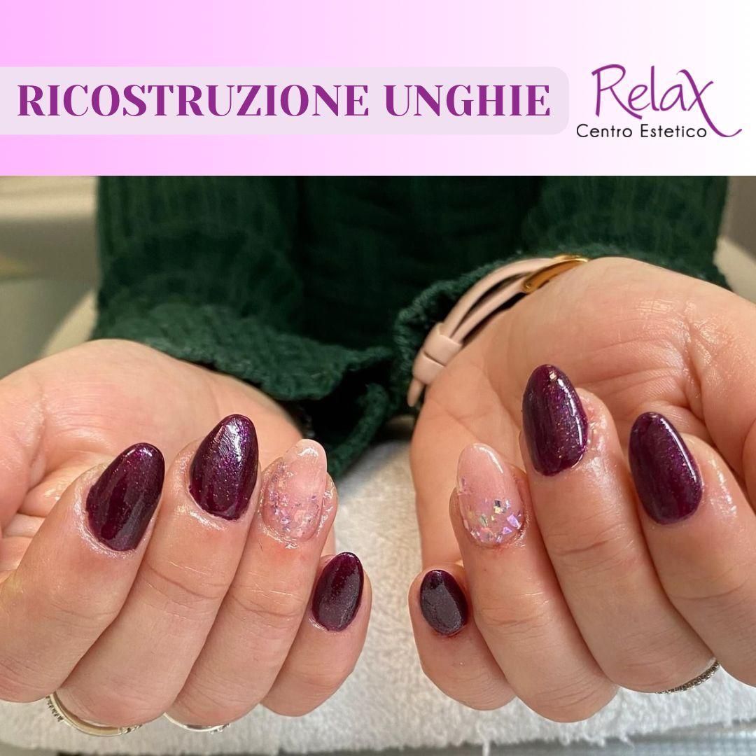 Mani con unghie lucide viola scuro e unghie decorate con glitter, mostrate in un primo piano di una manicure.