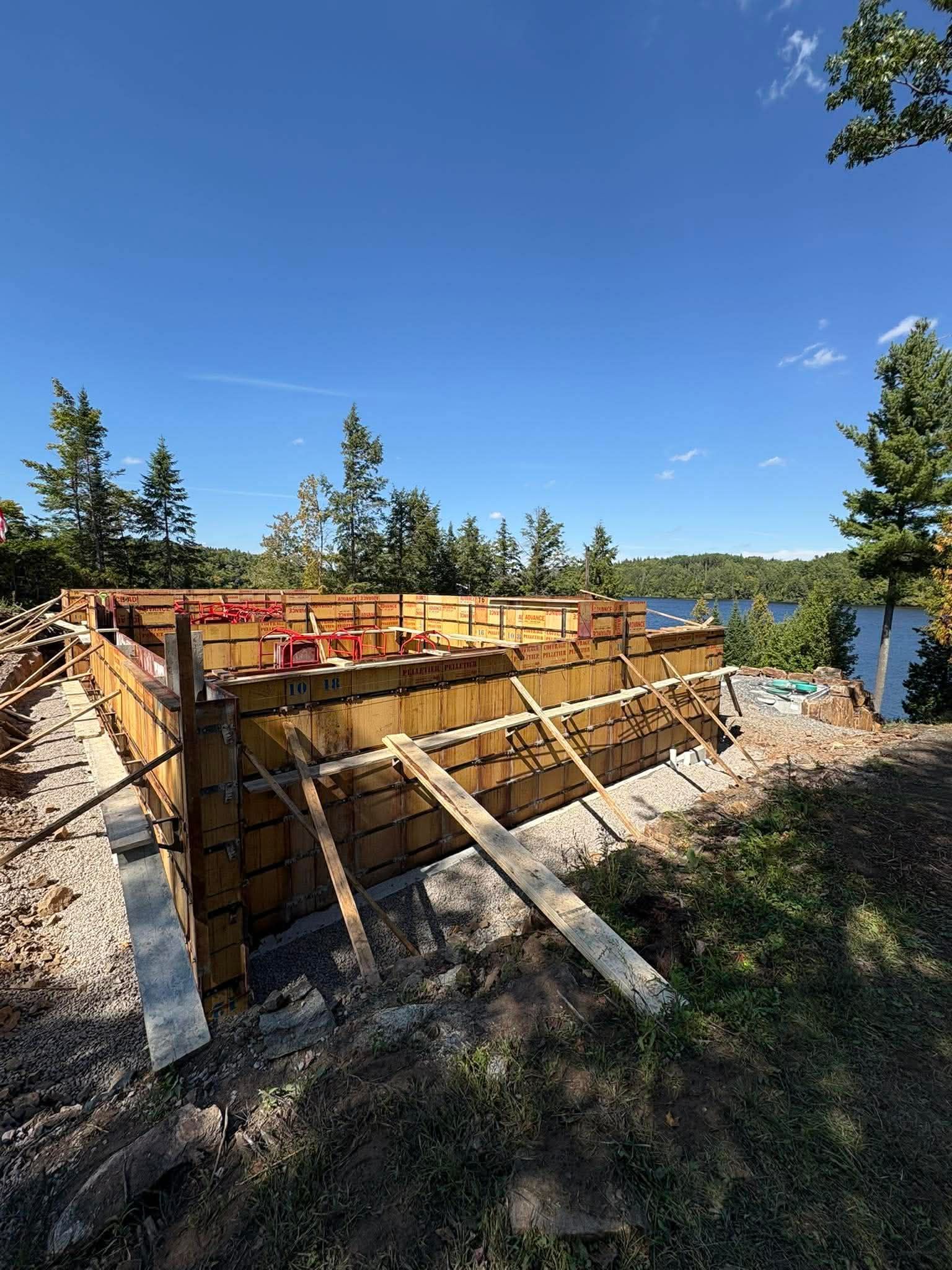 Fondation en bois en construction avec étaiement sur un site ensoleillé au bord d'un lac