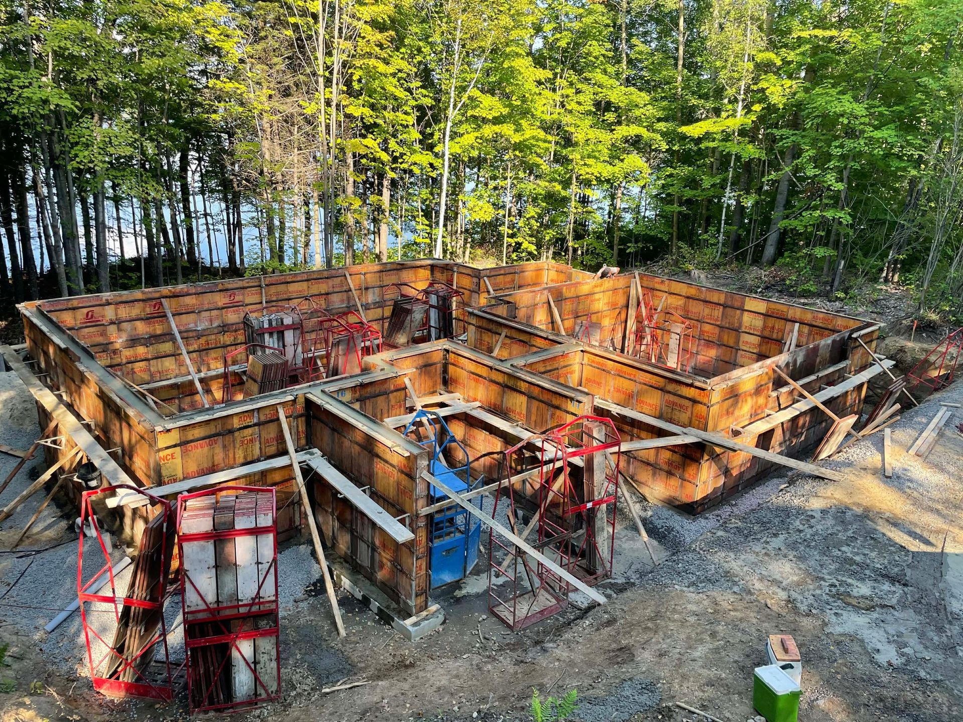 Fondations en béton partiellement construites avec coffrage rouge dans une zone boisée