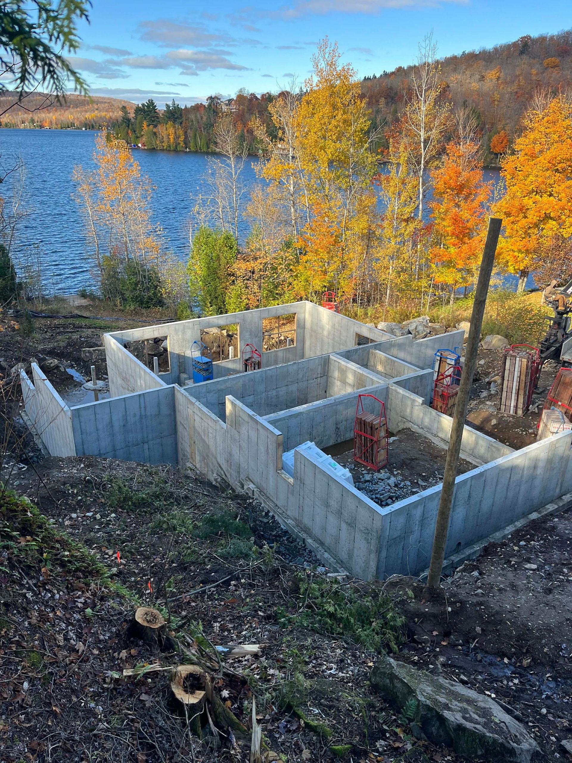 Murs de fondation en béton sur un chantier de construction au bord d'un lac, au milieu des arbres d'automne
