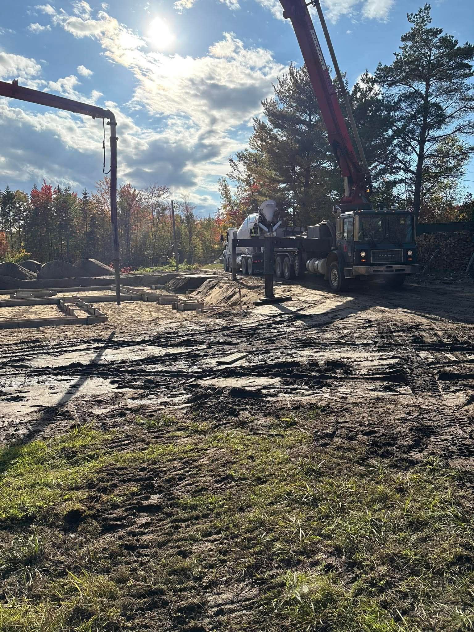 Ouvrier près d'un camion-grue sur un chantier boueux en plein soleil