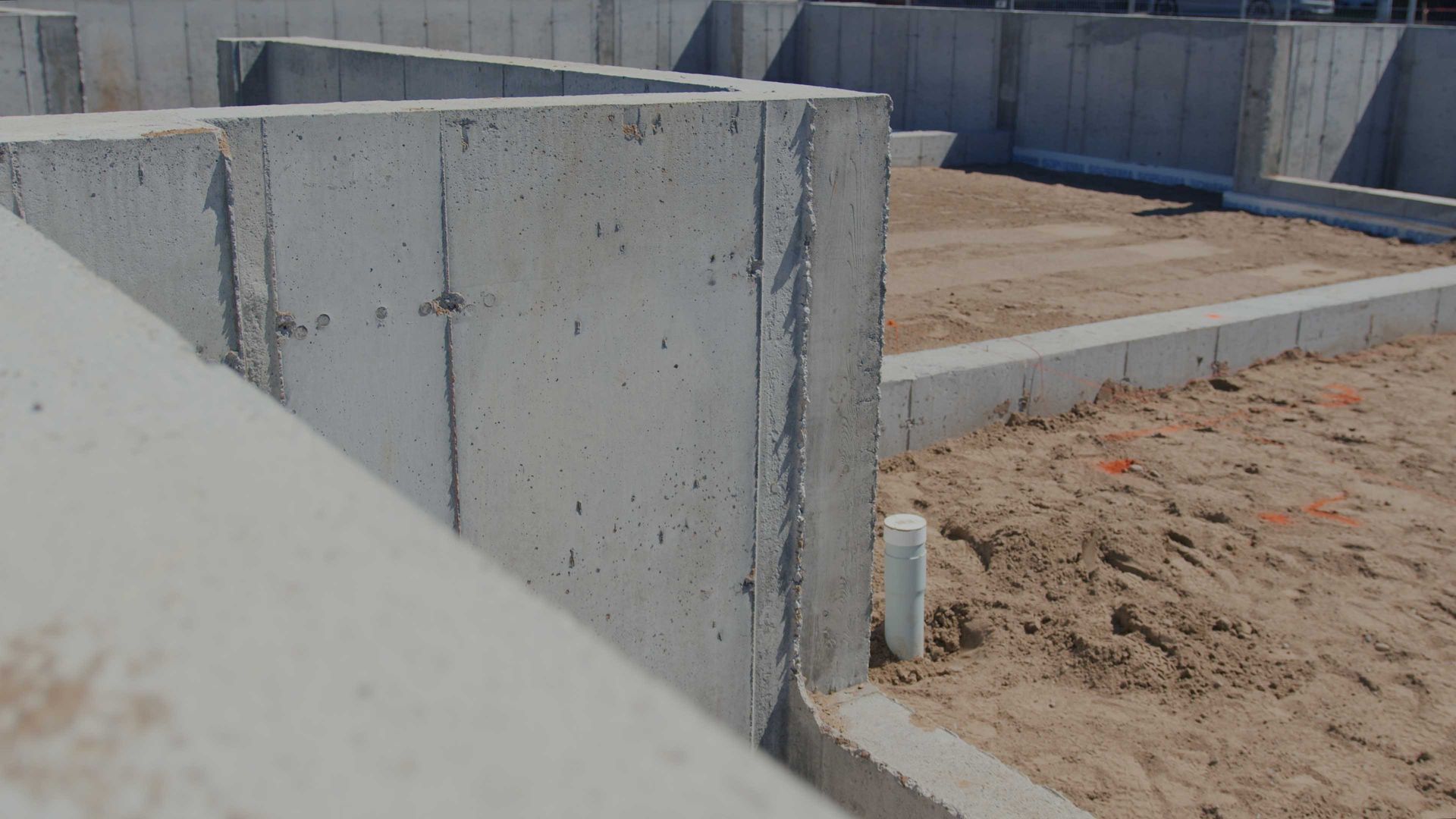 Mur de soutènement en béton à côté d'une tranchée de fondation en terre sur un chantier de construction