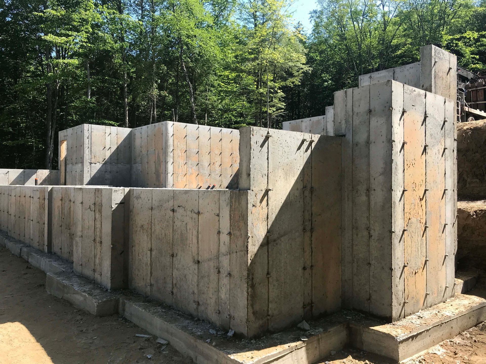 Murs de fondation en béton en construction à côté d'une zone boisée