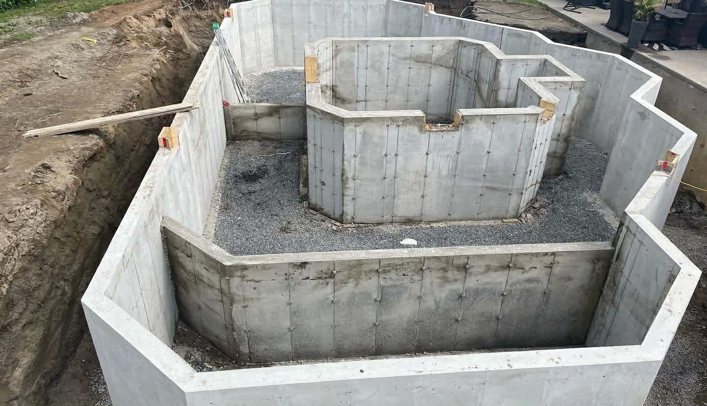Murs de fondation en béton formant une structure octogonale à gradins sur un terrain en gravier en construction