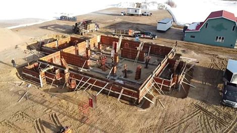 Vue aérienne d'une fondation en bois partiellement construite sur un terrain sablonneux près d'une maison