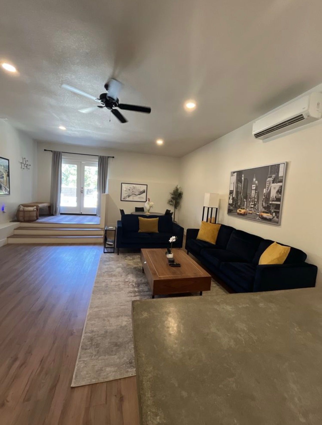 Living room with navy sofas, gray rug, wood coffee table, and large window.