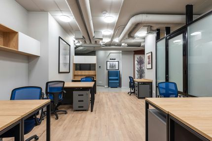 Office space with multiple desks, blue chairs, and a neutral color scheme.