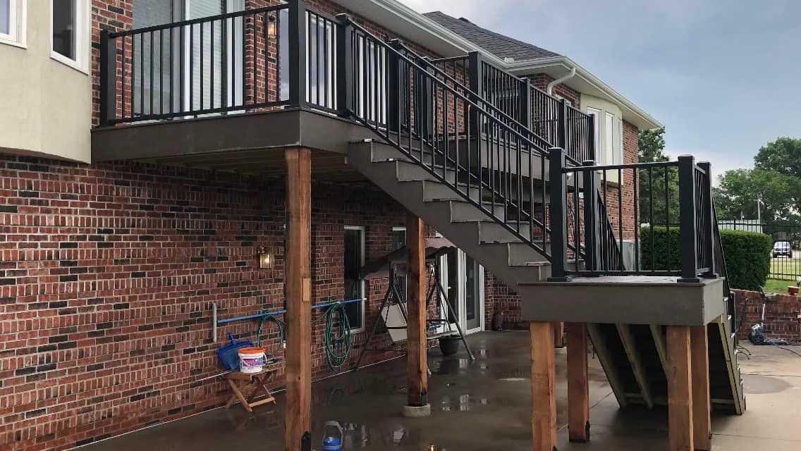 A brick house with a deck and stairs leading up to it.