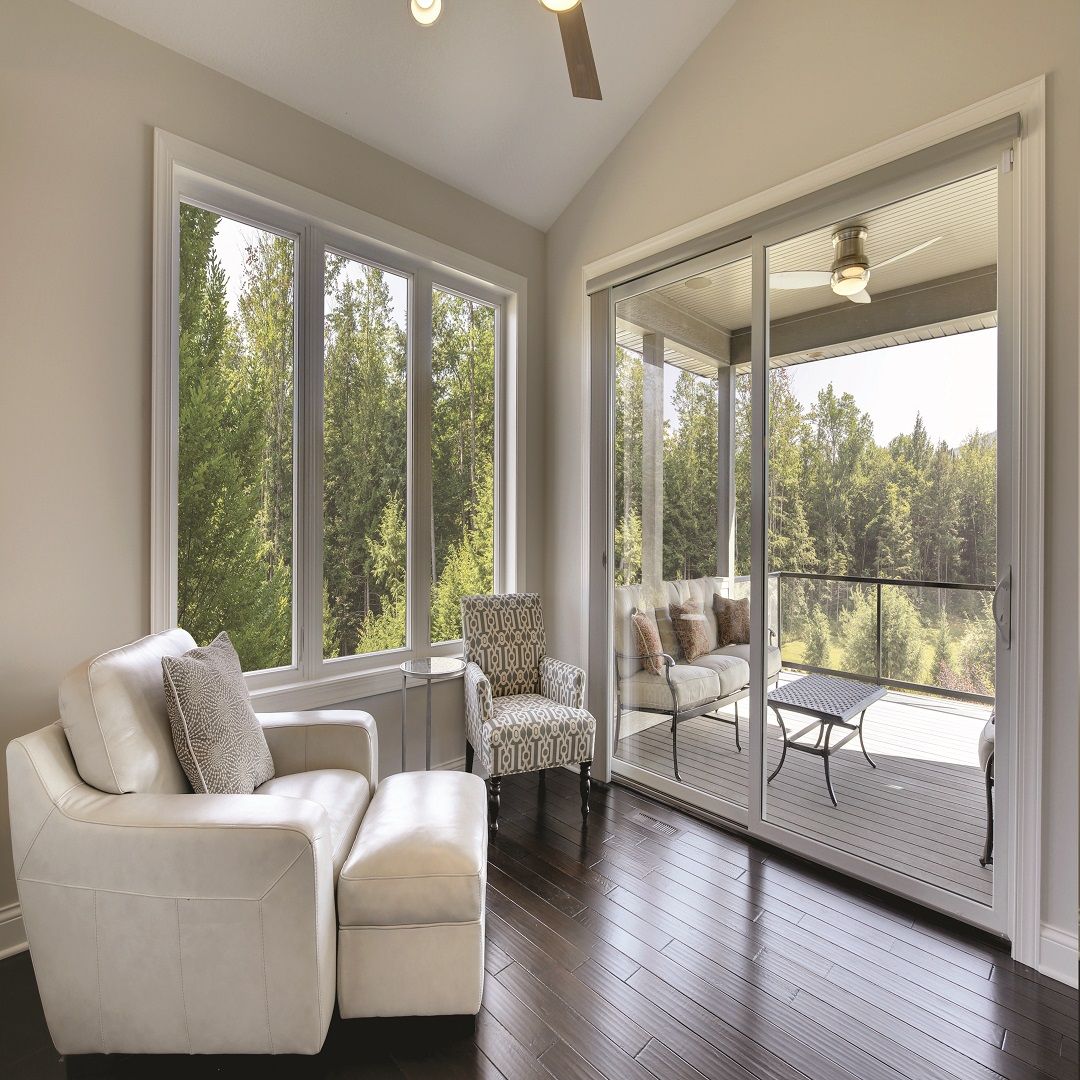 A living room with a couch , chair , ottoman and sliding glass doors.
