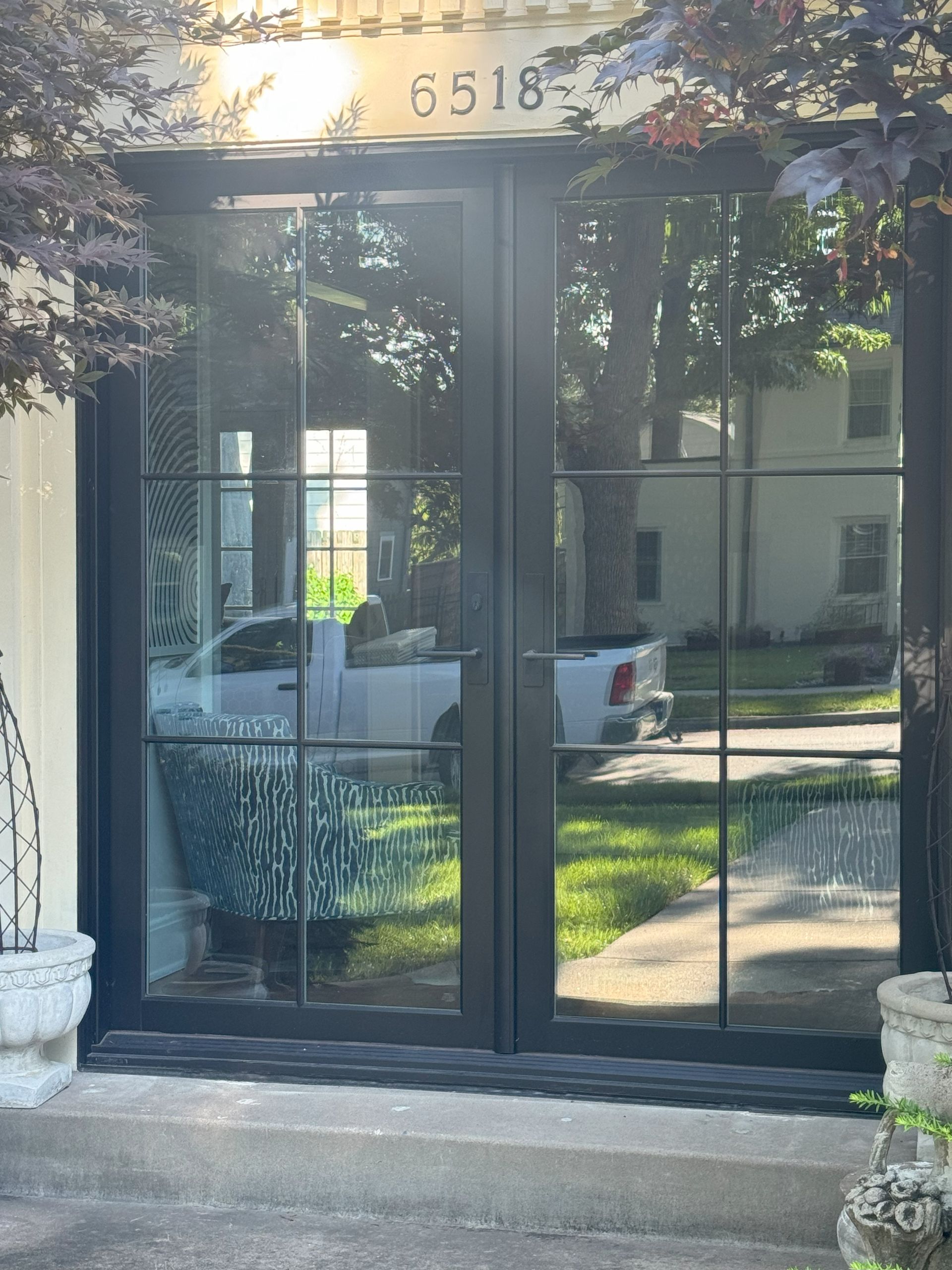 Black double doors with glass panes, reflecting a street scene. Building number 6518 above the doors.