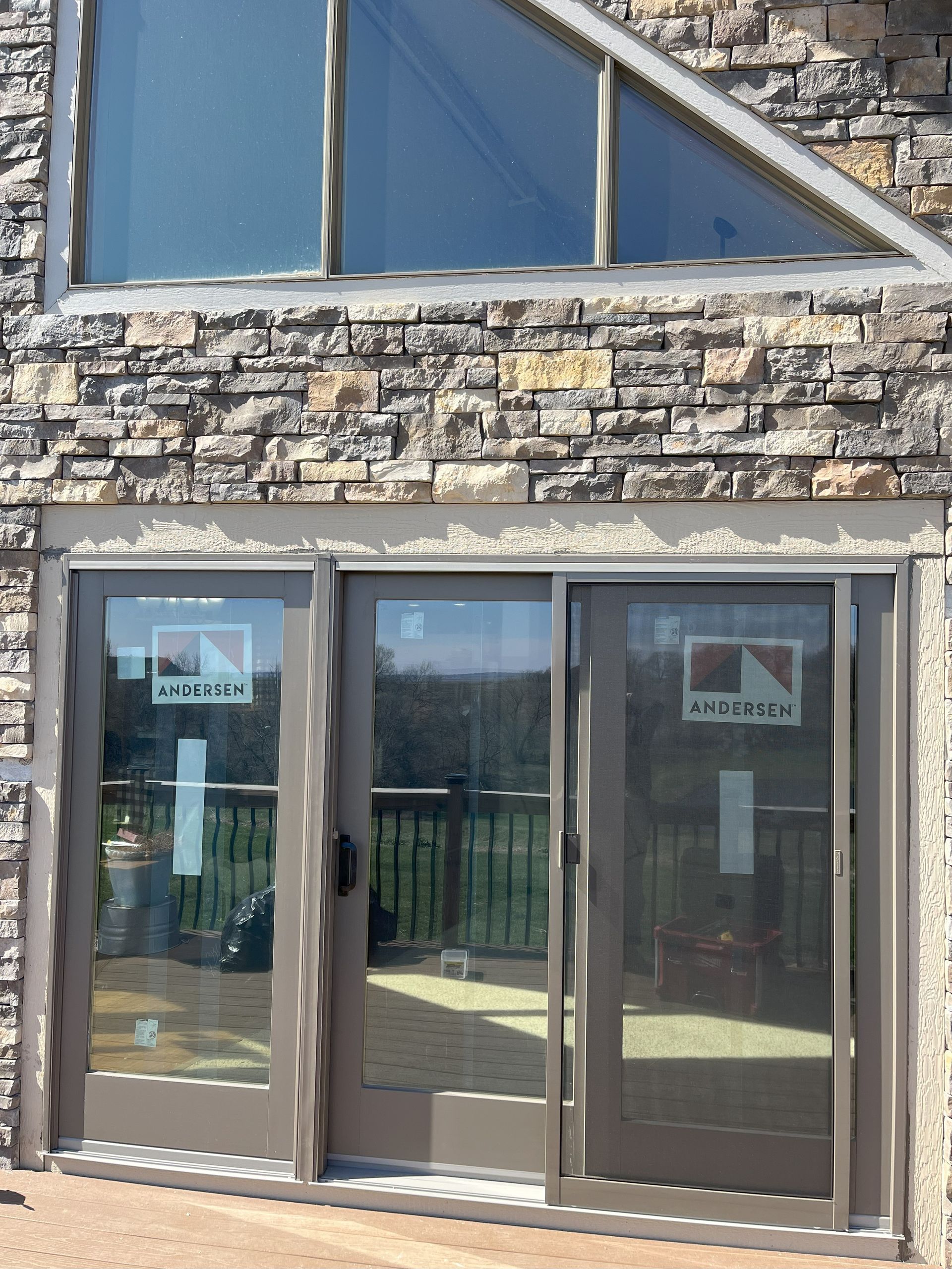 Three glass doors with a stone wall and triangular window above.