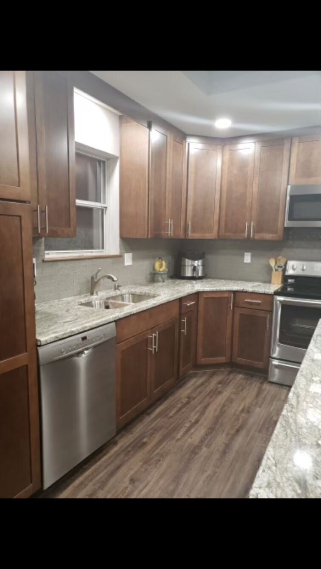 Kitchen with brown cabinets, stainless steel appliances, and gray countertops.