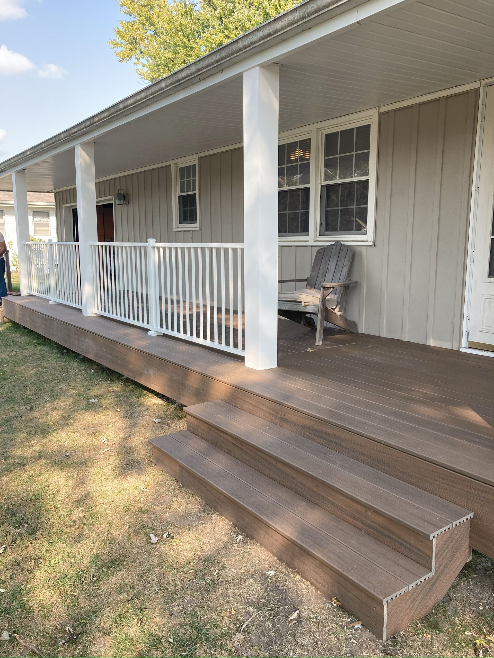 Composite deck with steps and white railing on a house porch.