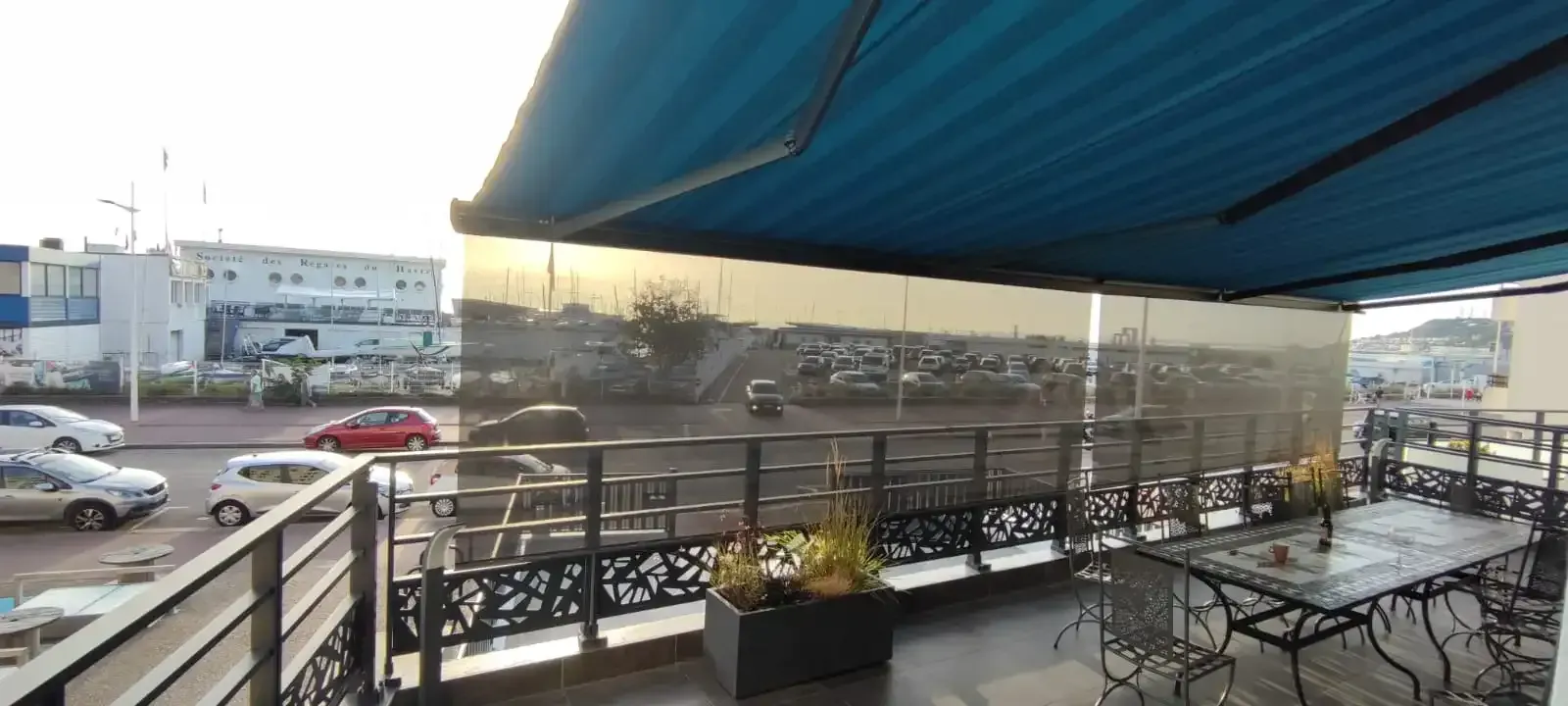 Un balcon avec tables et chaises sous un store extérieur au Havre
