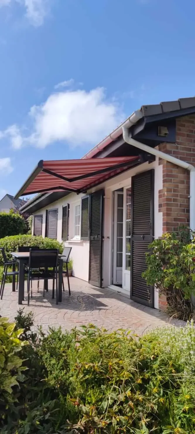 Une maison avec un patio avec une table et des chaises sous un store extérieur au Havre.
