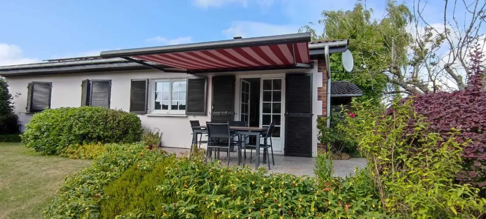 Une petite maison blanche avec un store extérieur rouge au-dessus du porche au Havre