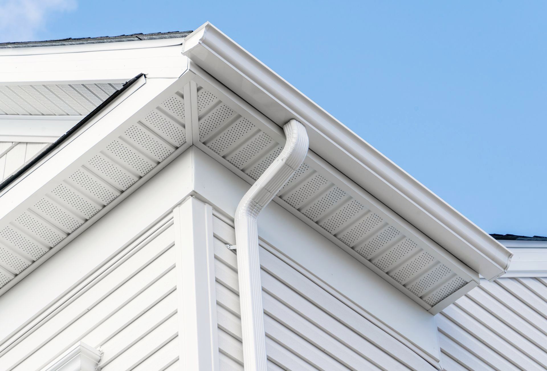 A white house with a gutter on the side of it