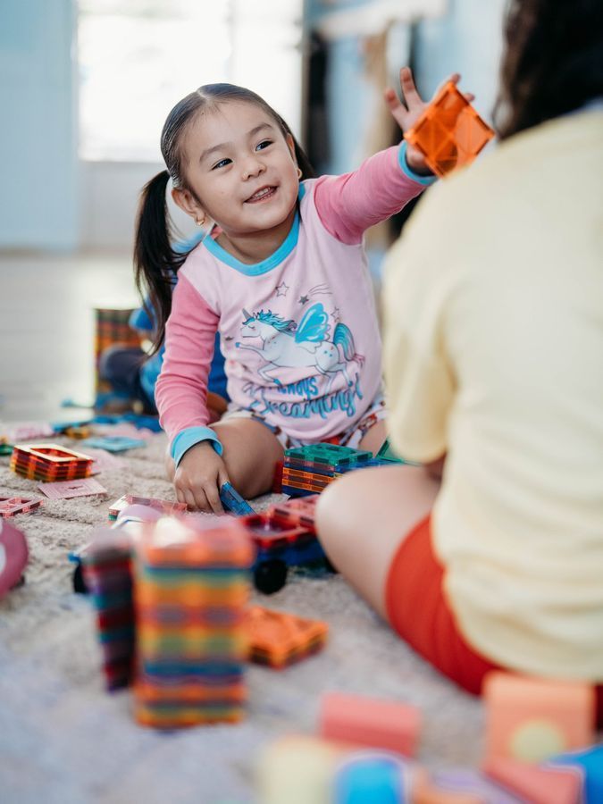 A smiling preschooler playing with building blocks