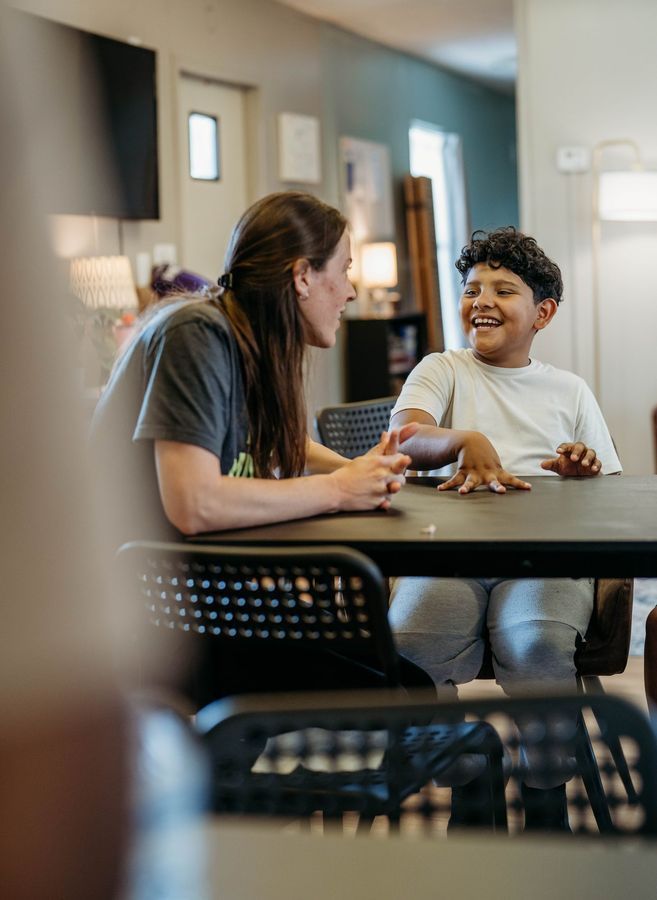 A teacher and student laughing together at a table