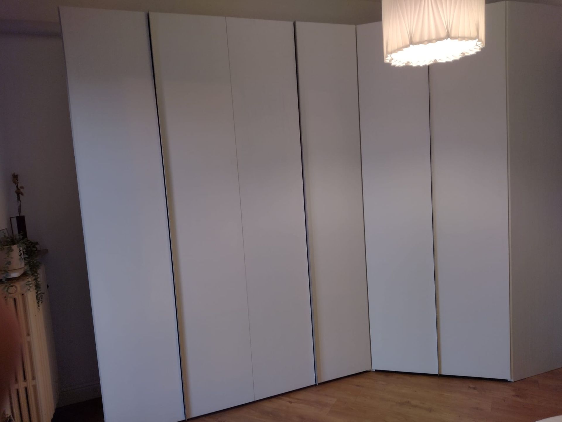 Una stanza con tanti armadietti bianchi e una lampada appesa al soffitto.